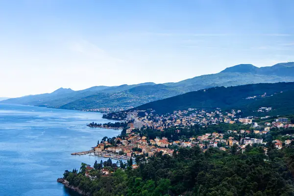 stock image Panoramic view of Opatijas coastline in Croatia, nestled between green hills and the Adriatic Sea. Vibrant buildings and peaceful water.