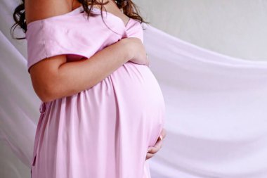 Zarif hamile kadın sonsuz beyaz bir elbise içinde elleri nazikçe karnını sarıyor. Bu portre umut ve beklenti yayıyor, annelik sevgisi ve beklentinin özünü özetliyor..  