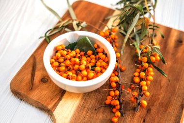 Bir dalda taze toplanmış deniz dikenli meyveler. Sonbaharda hasat edilen ve dallardan koparılan deniz dikenli karabatak, donmaya ve şifalı çay yapmaya hazır bir tabağa döküldü. Üst görünüm