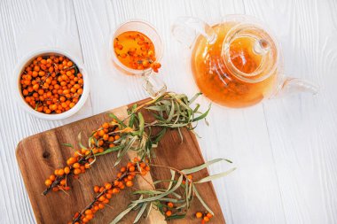 berrak bir çaydanlıkta demlenen deniz dikenli çay, lezzetli bir karışım. Taze deniz dikenli yaprak ve böğürtlenli çay zamanı.