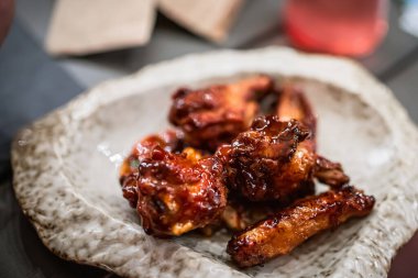  Koyu soslu birkaç tavuk kanadı ile beyaz tabak..