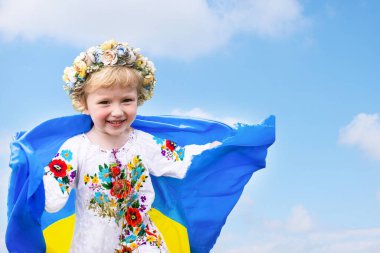 Sarı mavi Ukrayna bayrağı ezilmiş buğday tarlasında koşan kızın ellerinde. Ukrayna bayrağı taşıyan mutlu çocuk. Bağımsızlık Günü. Bayrak Günü. Anayasa Günü