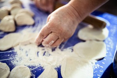 Üzerinde un serpiştirilmiş mavi bir paspasın üzerinde duran hamur mermileri üzerinde bir el sıkışır.