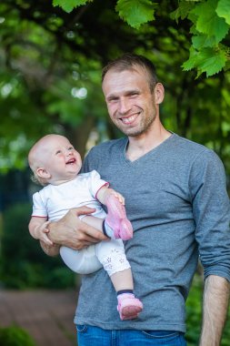 Babam kucağında gülen bir bebek tutuyor. Babasının kızına olan sevgisi. Aile genç baba ve küçük şirin çocuk portresi.