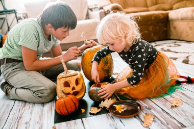 Cadılar Bayramı için balkabağı oymak. Cadılar Bayramı 'na hazırlanan çocuklar, balkabağının tepesini çıkarıyorlar. Balkabağı kabağına korkunç bir yüz çizmek için oyulmuş. Adım adım. Adım 2
