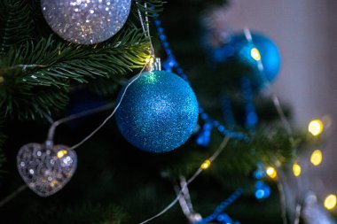 Güzel dekore edilmiş bir Noel ağacı parlak mavi süsler ve parlak ışıklar içerir, neşeli bir tatil atmosferi yaratır. Işıldayan süslemeler şenlik ruhunu güçlendirir..