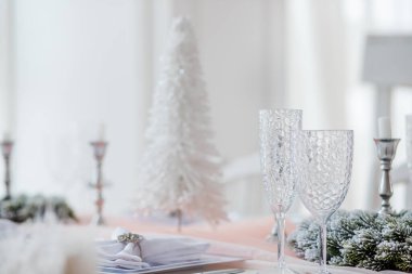 A beautifully arranged table showcases a delicate white tree, candle holders, and neatly folded napkins. Soft lighting enhances the festive atmosphere, perfect for seasonal celebrations. clipart