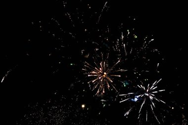 Karanlık gökyüzüne karşı canlı renklerde havai fişekler patlıyor, özel bir olayı kutluyorlar. Parlak ışıklar, yukarıdaki güzelliği takdir eden izleyicileri cezbeden neşeli bir atmosfer yaratır..