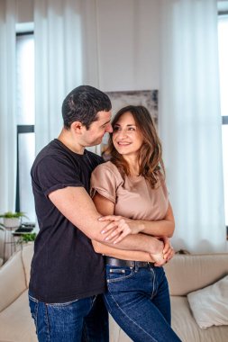 Doğal ışıkla dolu parlak bir odada, bir çift, Sevgililer Günü 'nde aşklarını kutlarken sevinçle kucaklaşır. Gülüşleri, sıcak bir atmosferle çevrili iken sevgi ve bağlantıyı yansıtır..