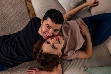 Sevgililer Günü 'nde bir çift romantik bir anın tadını çıkarır. Yumuşak bir kanepede uzanıyorlar, rahat bir dekorla çevrili, derin sevgilerini ve ilişkilerini yansıtan gülümsemelerini paylaşıyorlar..