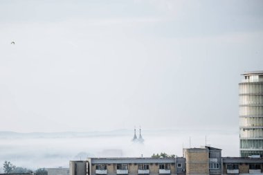 Şafak vakti Osijek 'in çatılarında uçan kuş siluetleri, açık gökyüzü ve arka planda kentsel ufuk çizgisi. 