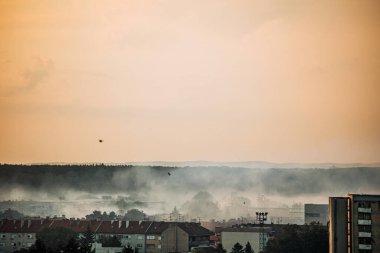 Osijek şehrinin üzerinde turuncu bir güneş doğuyor. Sivrisinekleri kontrol etmek için görünür bir sis bulutu oluşuyor. Dramatik bir sabah sahnesi yaratıyor..