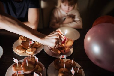 Neşeli bir doğum günü partisinde küçük bayraklarla süslenmiş lezzetli kekler yer alır. Bir kardeş mum yakarken diğeri hevesle izliyor ve heyecanla dolu unutulmaz bir an yaratıyor..
