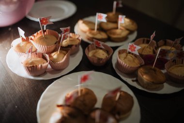Yeni pişmiş keklerle dolu bir masa. Her birinin üstünde küçük bayraklar var. Oturma odasındaki aile toplantısını canlandırıyor.. 