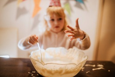Çocuk pasta hamurunu bir kasede karıştırırken, doğum günü kutlaması için hazırlanıyor.. 