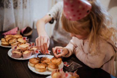 İki kardeş aile toplantılarında küçük bayraklarla kek süslemekten hoşlanırlar. Sıcak atmosfer ve lezzetli ikramlar bu özel durum sırasında neşeli bir deneyim yaratıyor..