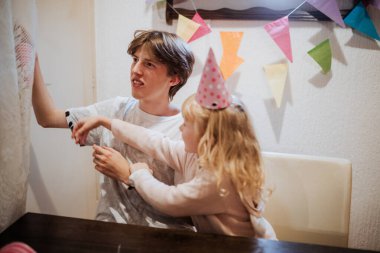 İki kardeş, bir aile toplantısında birlikte kutlama yapmaktan zevk alır. Renkli dekorasyonlar rahat evlerindeki neşeli atmosferi arttırır..