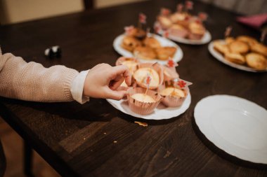Çocuk, festival masasında tabaktan keke uzanıyor..