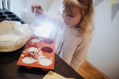Genç bir çocuk hamur kalıbını dikkatlice pişirerek lezzetli yiyecekler yaratmaya odaklanıyor.. 