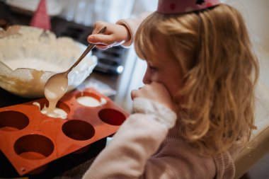 Genç bir çocuk hamur kalıbını dikkatlice pişirerek lezzetli yiyecekler yaratmaya odaklanıyor.. 