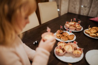 Çocuk, festival masasında tabaktan keke uzanıyor..