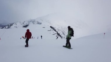 Snowboardcu Alplerin tozlu yamaçlarının tadını çıkarıyor.