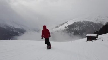 Snowboardcu Alplerin tozlu yamaçlarının tadını çıkarıyor.