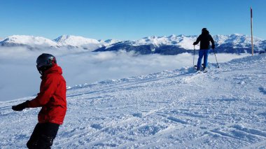 Snowboardcu Alplerin tozlu yamaçlarının tadını çıkarıyor.