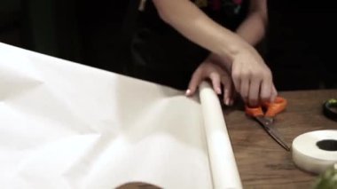 Çiçekçide buket yapar.