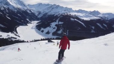 Snowboardcular Alplerin tozlu yamaçlarının tadını çıkarıyorlar.