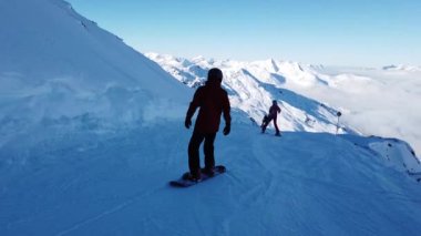 Snowboardcular Alplerin tozlu yamaçlarının tadını çıkarıyorlar.