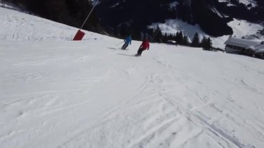 Snowboardcular Alplerin tozlu yamaçlarının tadını çıkarıyorlar.