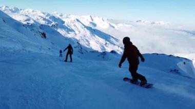 Snowboardcular Alplerin tozlu yamaçlarının tadını çıkarıyorlar.