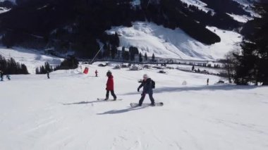 Snowboardcular Alplerin tozlu yamaçlarının tadını çıkarıyorlar.