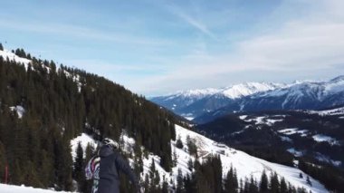 Snowboardcu Alplerin tozlu yamaçlarının tadını çıkarıyor.