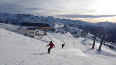 Snowboardcu Alplerin tozlu yamaçlarının tadını çıkarıyor.