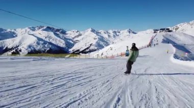 Snowboardcu Alplerin tozlu yamaçlarının tadını çıkarıyor.