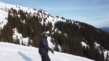 Snowboardcu Alplerin tozlu yamaçlarının tadını çıkarıyor.