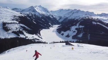 Snowboardcu Alplerin tozlu yamaçlarının tadını çıkarıyor.