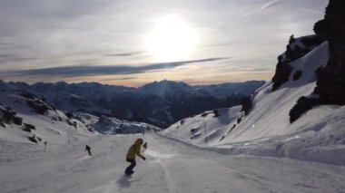 Snowboardcu Alplerin tozlu yamaçlarının tadını çıkarıyor.