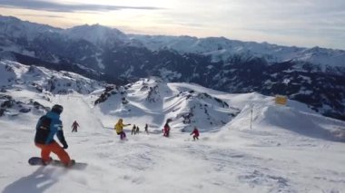 Snowboardcu Alplerin tozlu yamaçlarının tadını çıkarıyor.