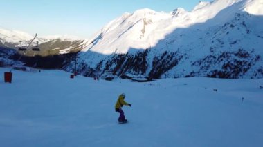 Snowboardcu Alplerin tozlu yamaçlarının tadını çıkarıyor.