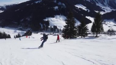 Snowboardcu Alplerin tozlu yamaçlarının tadını çıkarıyor.