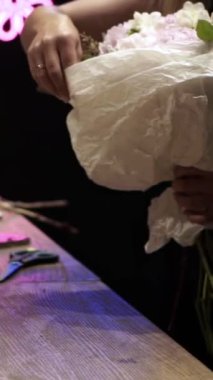 Sevgililer Günü için çiçek buketi yapan çiçekçinin yakın çekimi.