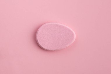 Pembe arka planda yumurta şeklinde kozmetik sünger. Üst görünüm