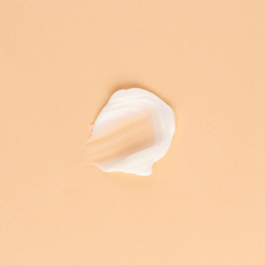 Kahverengi arka planda yüz ve vücut için beyaz krem kokusu