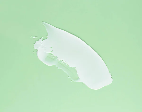 stock image Smear of white cream for face and body on a green background