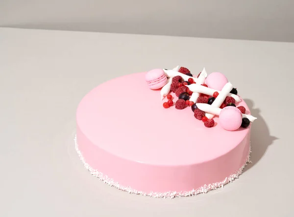 トップを飾る白いイチゴと食欲をそそるピンクのケーキは テーブルの上に座っています — ストック写真