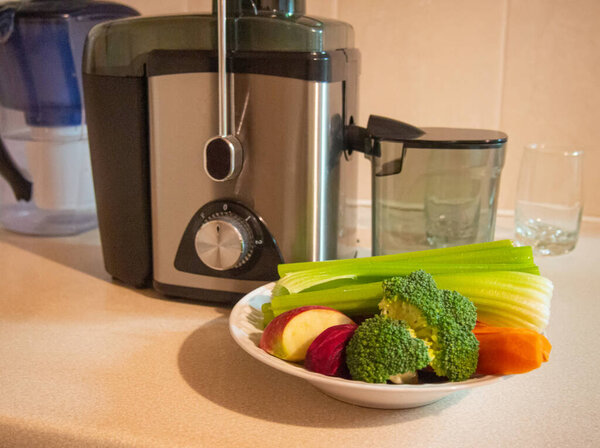 Juicer with plate of fresh vegetables. Preparing vegetable juice