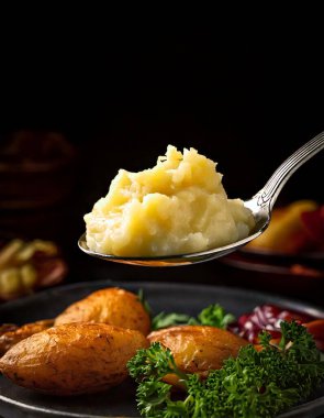 Koyu bir arka planda kaşıkta yakın plan patatesler. Yemek blogcuları için harika resimler.